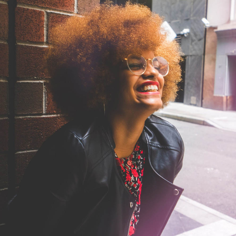 Happy, stylish woman with beautiful smile, laughing in an alleyway