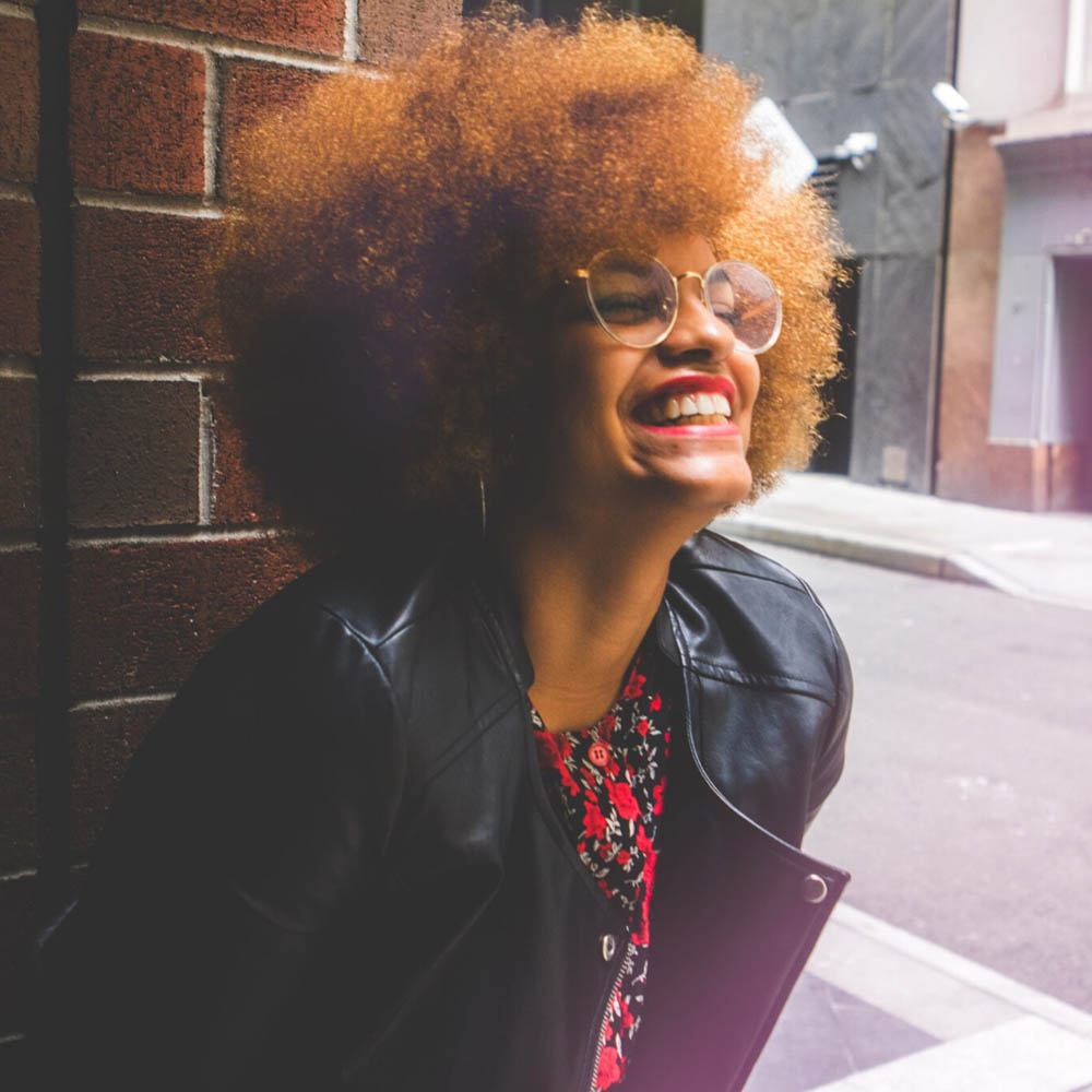 Happy, stylish woman with beautiful smile, laughing in an alleyway